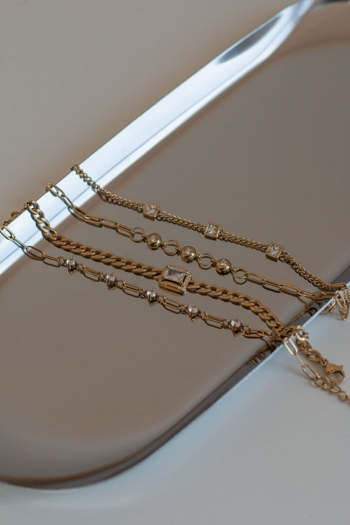 Gold chain bracelets laid out on a silver tray