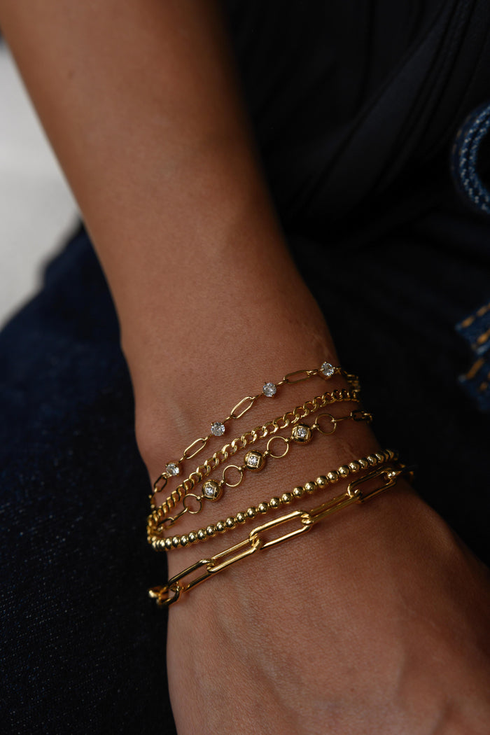 A wrist with multiple gold bracelets