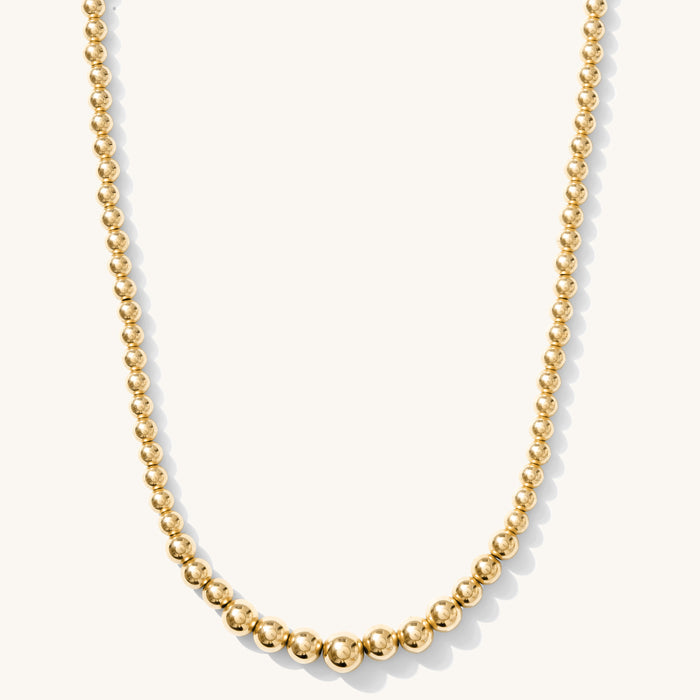 Close up of the gold Ombre bead necklace on a white background