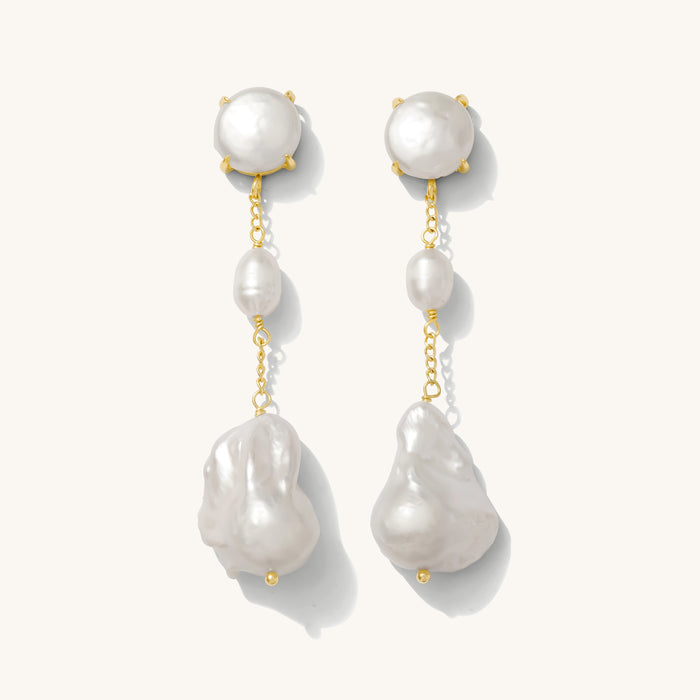 Close up of pearl dangle earrings on a white background