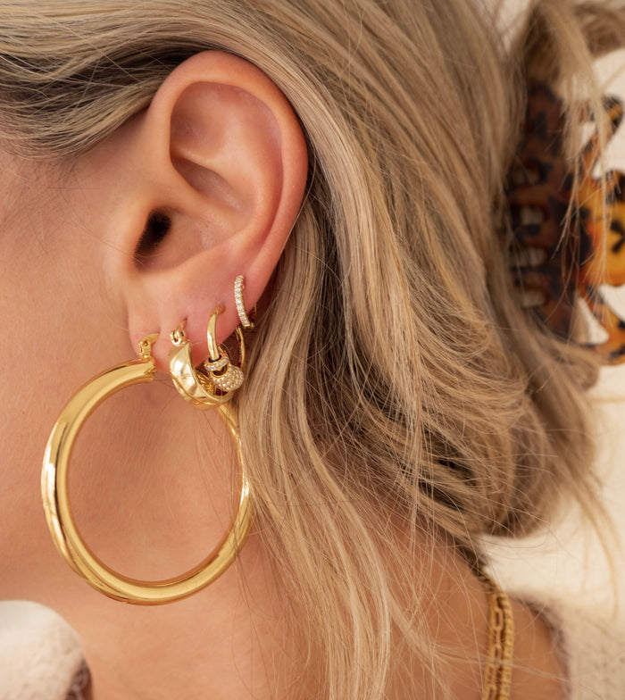 Close-up of an ear with multiple gold and crystal earrings