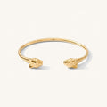 Close up of a gold cuff bracelet on a white background
