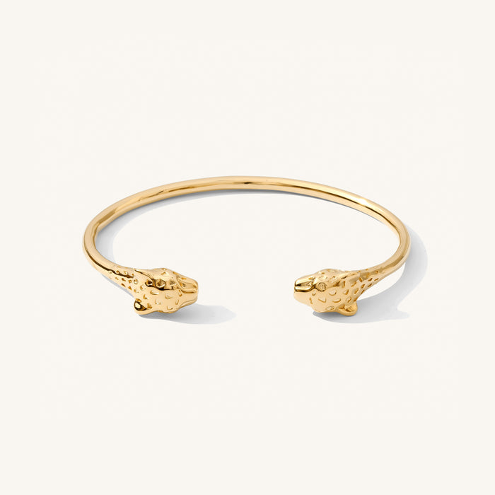 Close up of a gold cuff bracelet on a white background