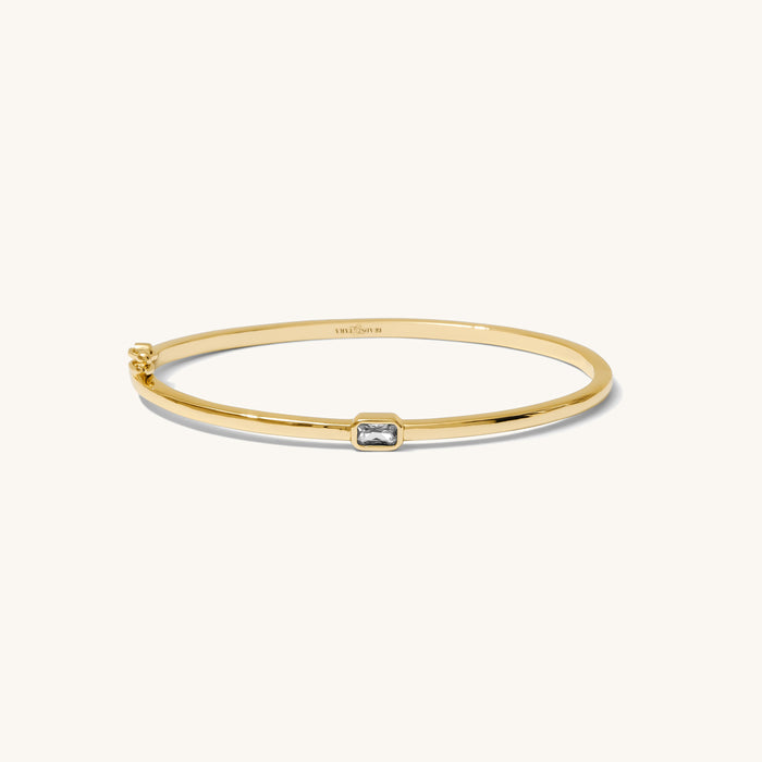 Gold bracelet with a small stone on a white background