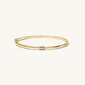 Gold bracelet with a small stone on a white background