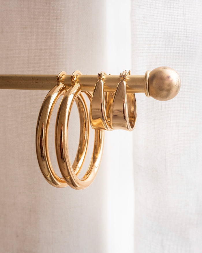 Two pairs of gold hoops on a gold jewelry rod
