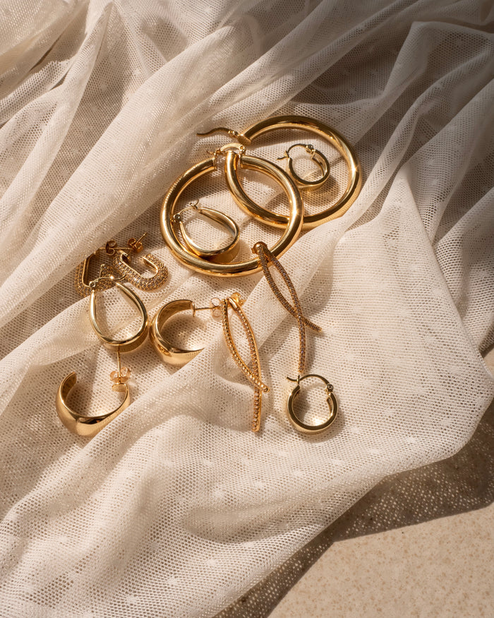 Various gold earrings on a sheer white cloth