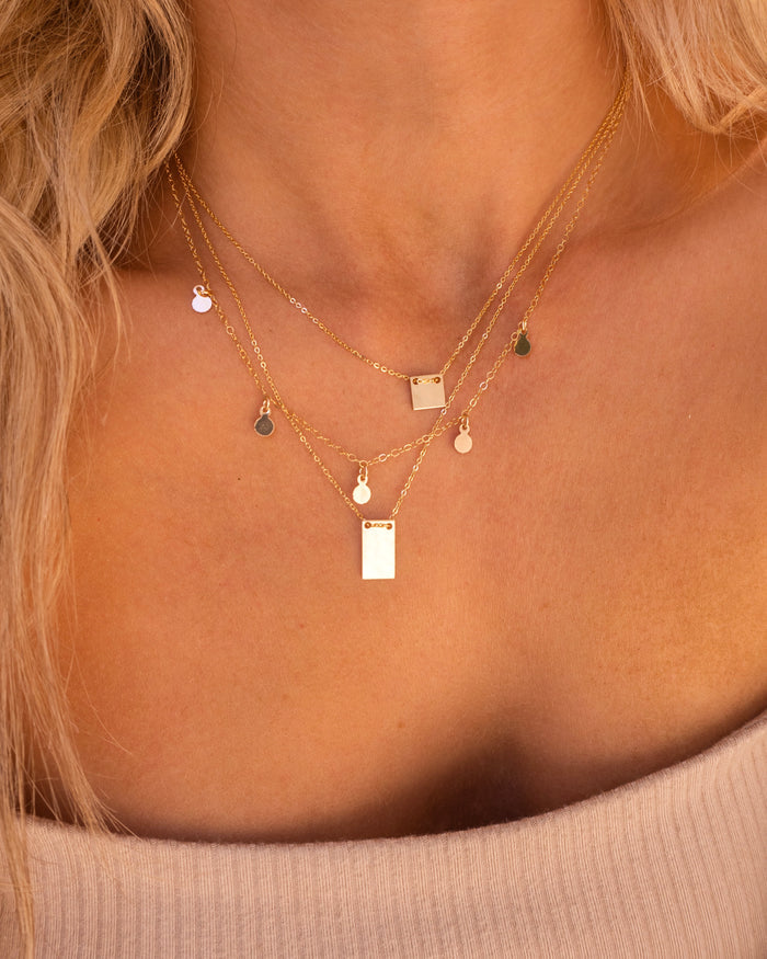 The Peyton square pendant necklace worn layered with dainty chains
