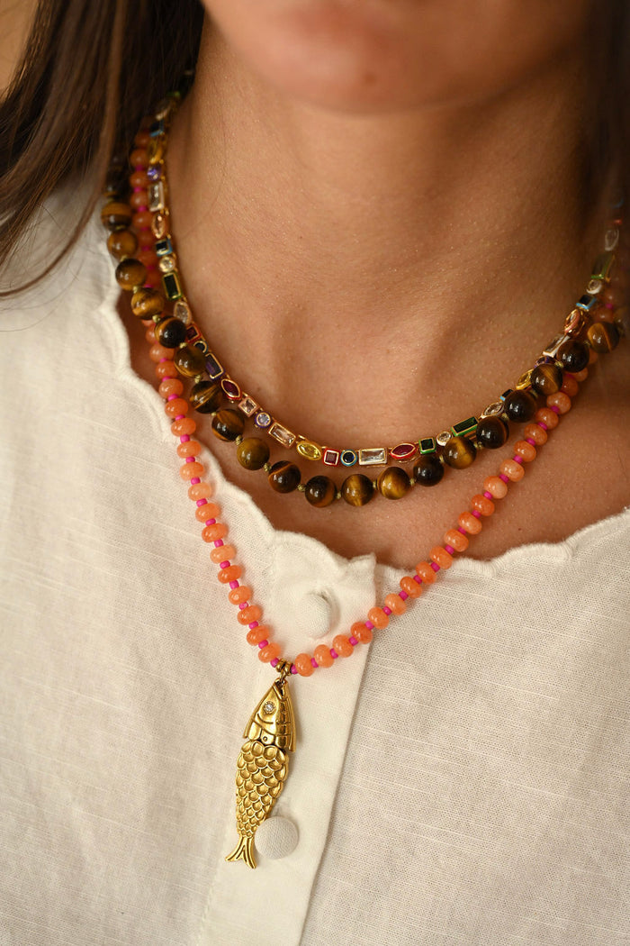Necklace with a gold fish pendant on a white shirt