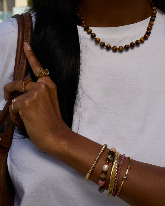 Person wearing multiple bracelets and rings on a white background