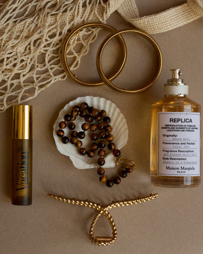 Perfume bottle, jewelry, and decorative items on a textured surface
