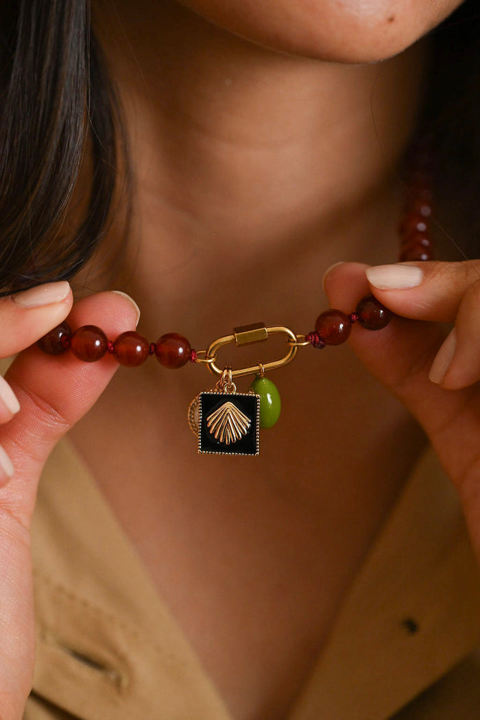Close-up of a person holding a beaded bracelet with a shell charm.