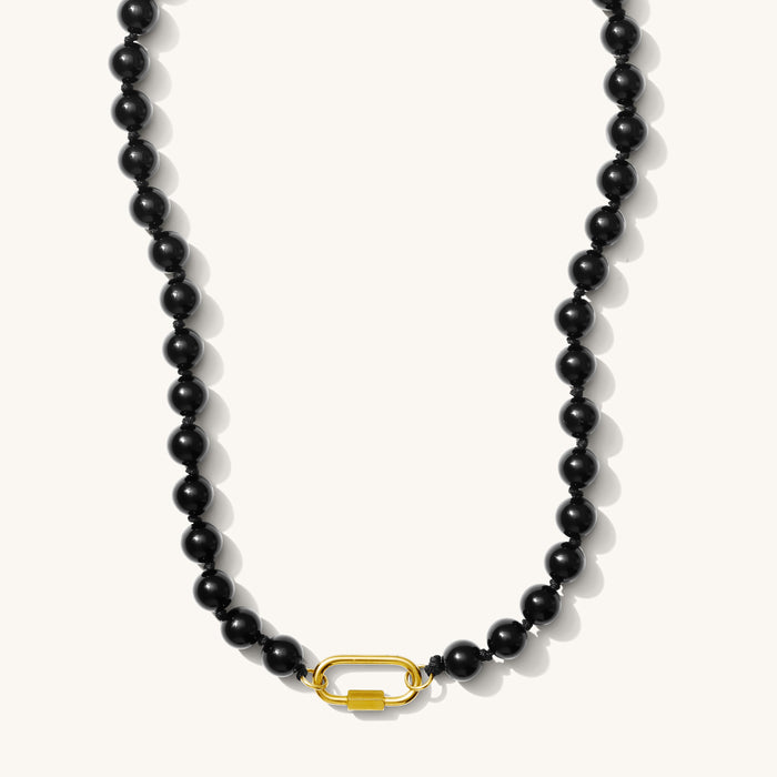 Close up of the Porto necklace in glossy obsidian black beads on a white background