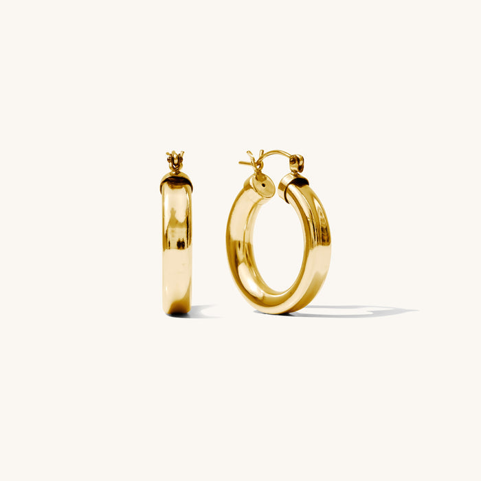 Close up of chunky gold hoop earrings on a white background