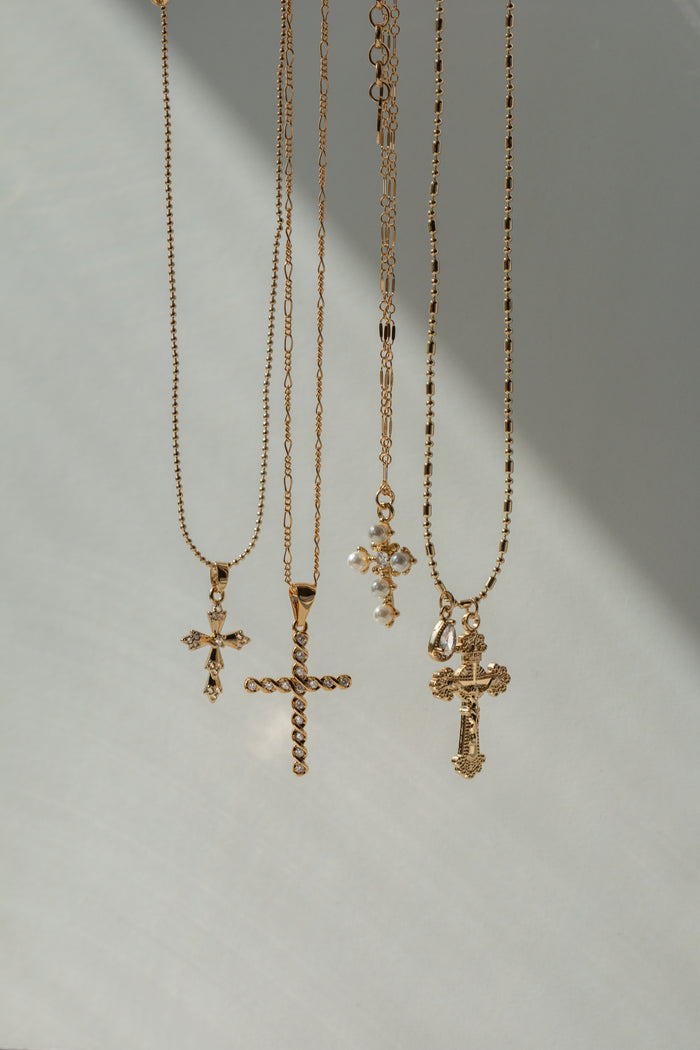 Pointed gold cross pendant trimmed with pearls on the Queen's Cross necklace