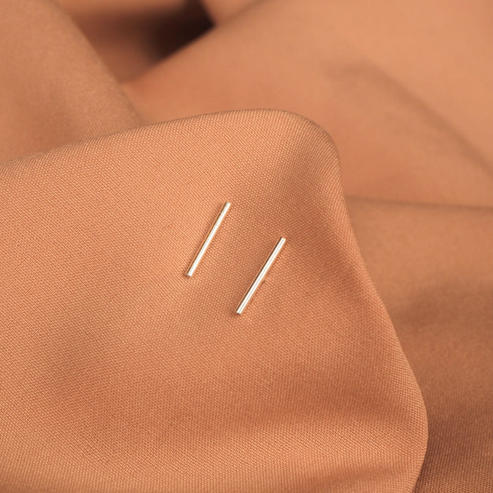 Close up of silver bar studs on a neutral cloth background