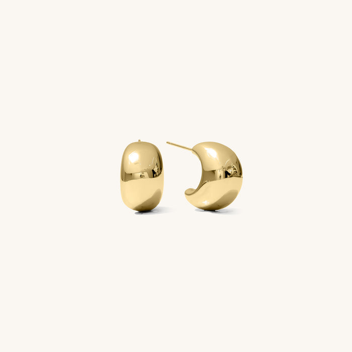 Close up of chunky gold hoop earrings on a white background