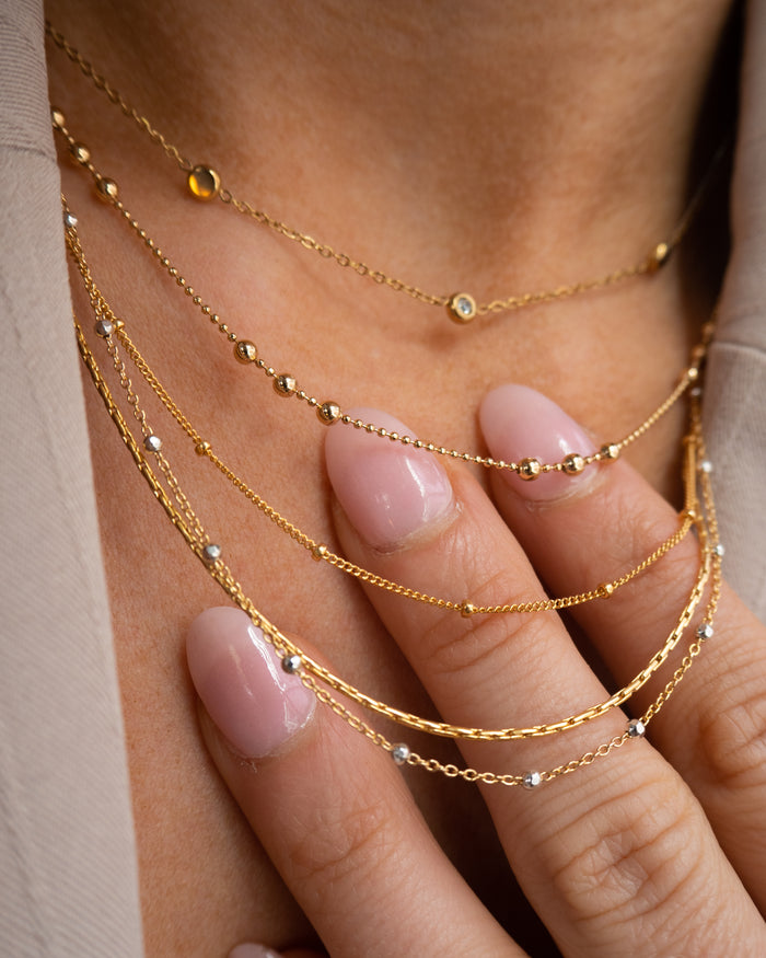 Model wearing the Riley necklace with silver disco beads on a gold chain