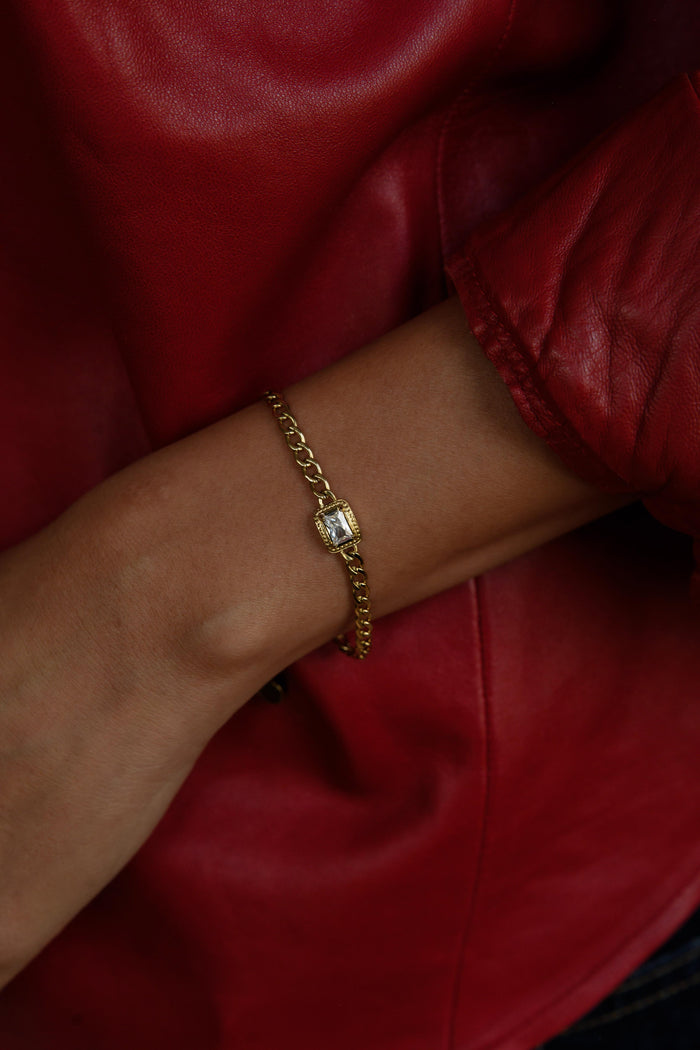 A person in a red shirt wearing a gold bracelet with stone accent