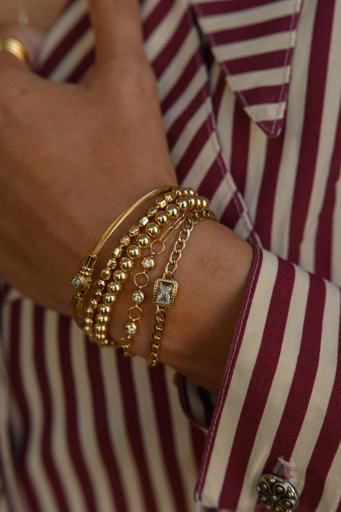 A person in a red and white striped shirt with gold bracelets