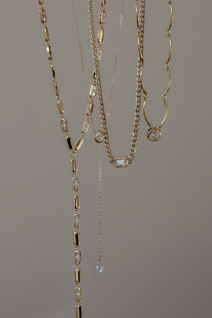 Structured gold cuban link chain anchored by a rectangular stone