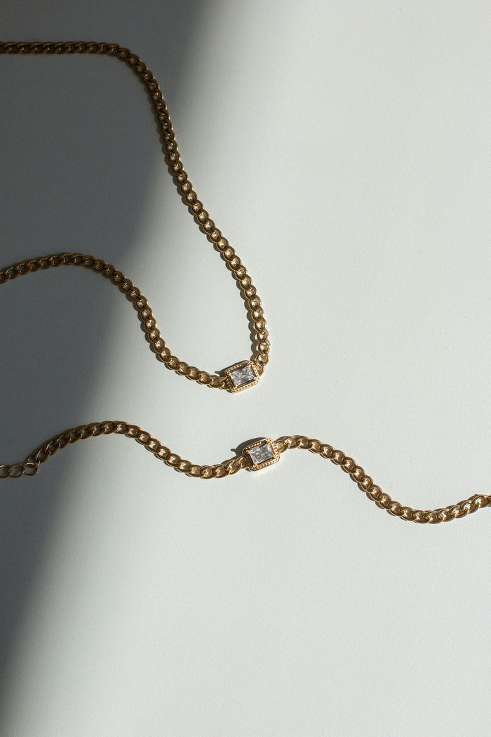 Two gold chain bracelets on a white background