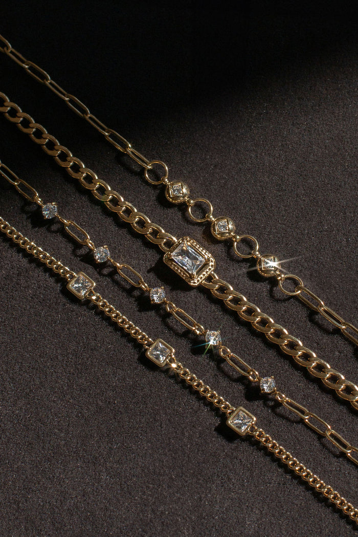 Gold bracelets with stone accents on a black background