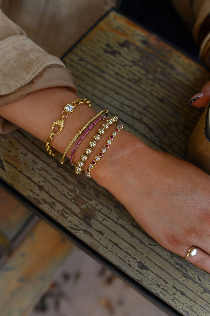 A wrist wearing various gold and stone bracelets