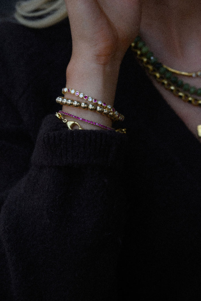 A wrist with multiple gold and stone bracelets