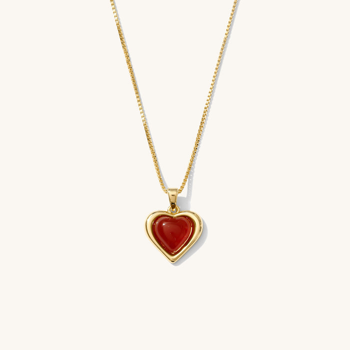 Close up of the gold Sacred Heart necklace on a white background