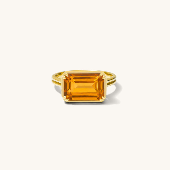 Close up of the Saffron ring with an east-west set gemstone on a white background