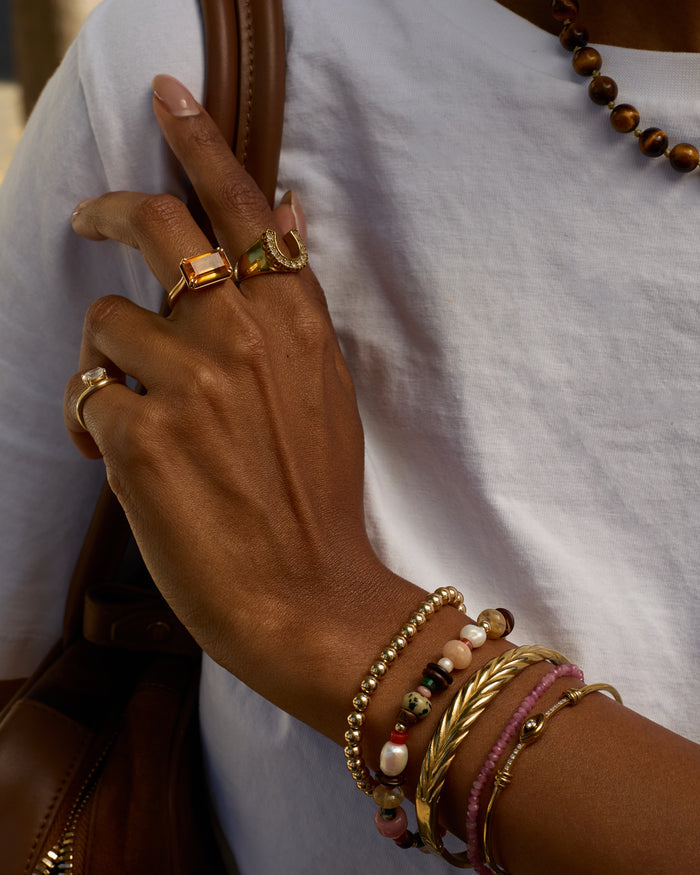 Hand with gold rings and bracelets on a white background