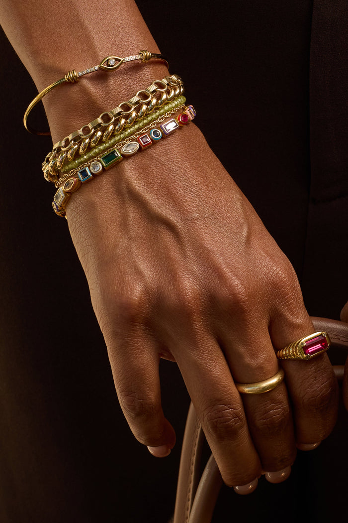 Close-up of hands wearing gold jewelry with a dark background
