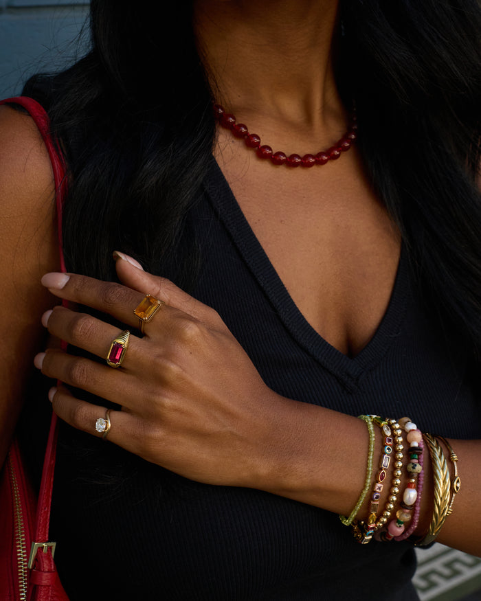 Close-up of a person wearing multiple rings and bracelets with a dark background