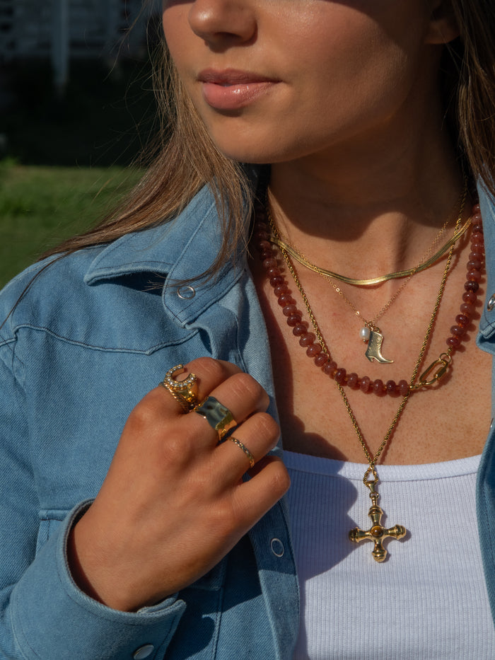 Close-up of a person wearing gold necklaces and rings outdoors
