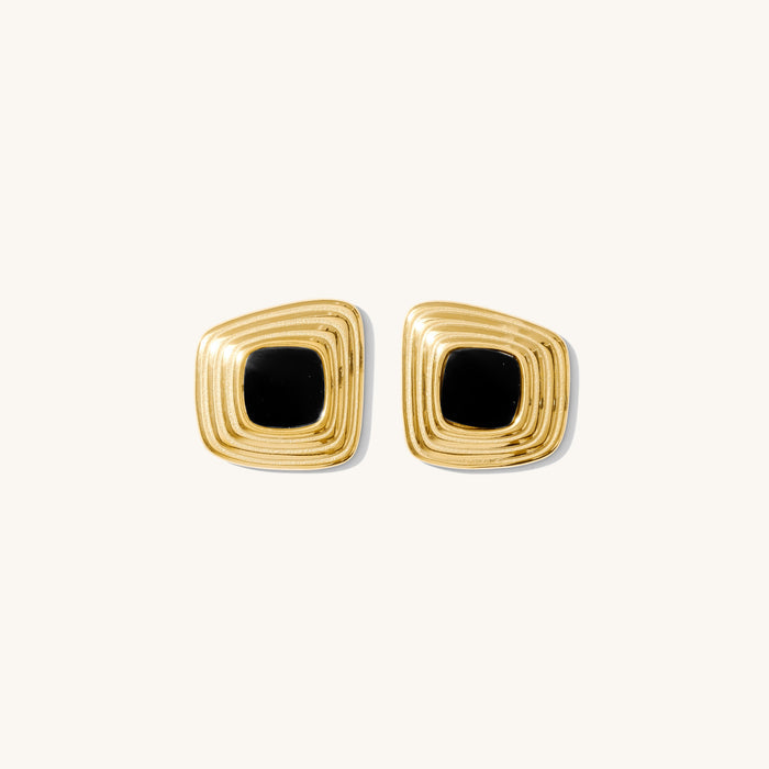 Close up of gold statement earrings on a white background