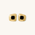 Close up of gold statement earrings on a white background