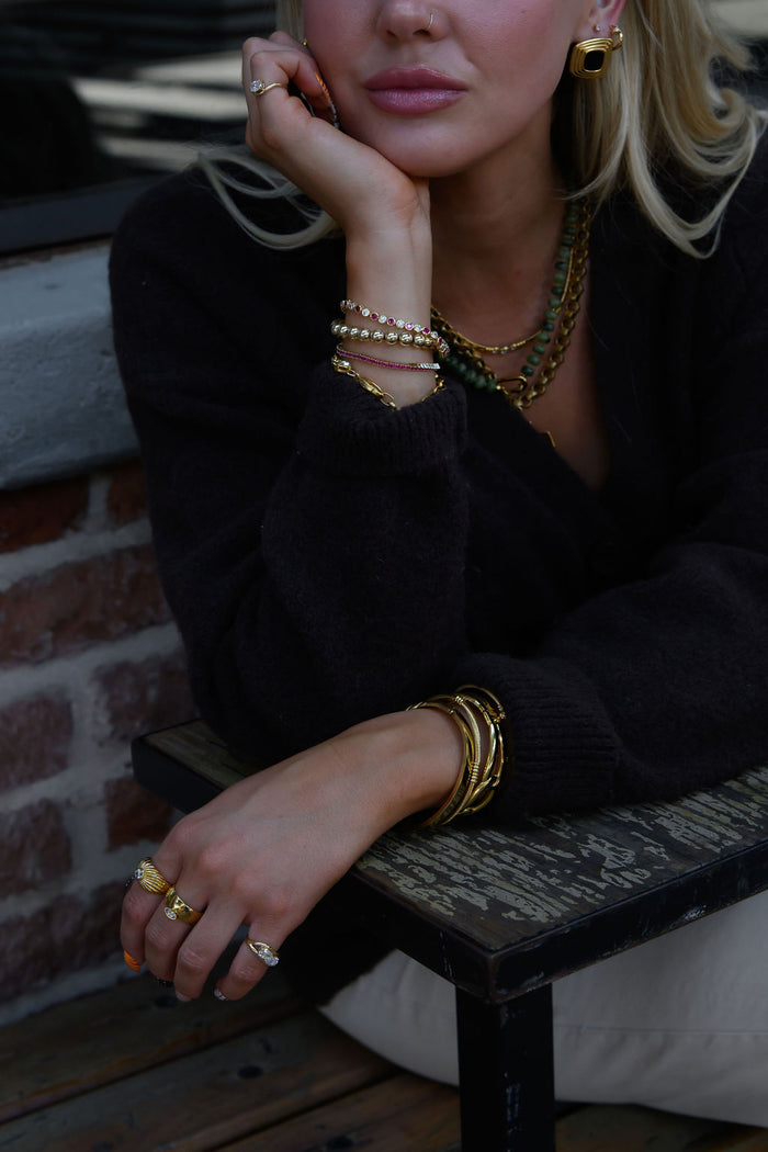 A woman wearing gold jewelry sitting on a bench