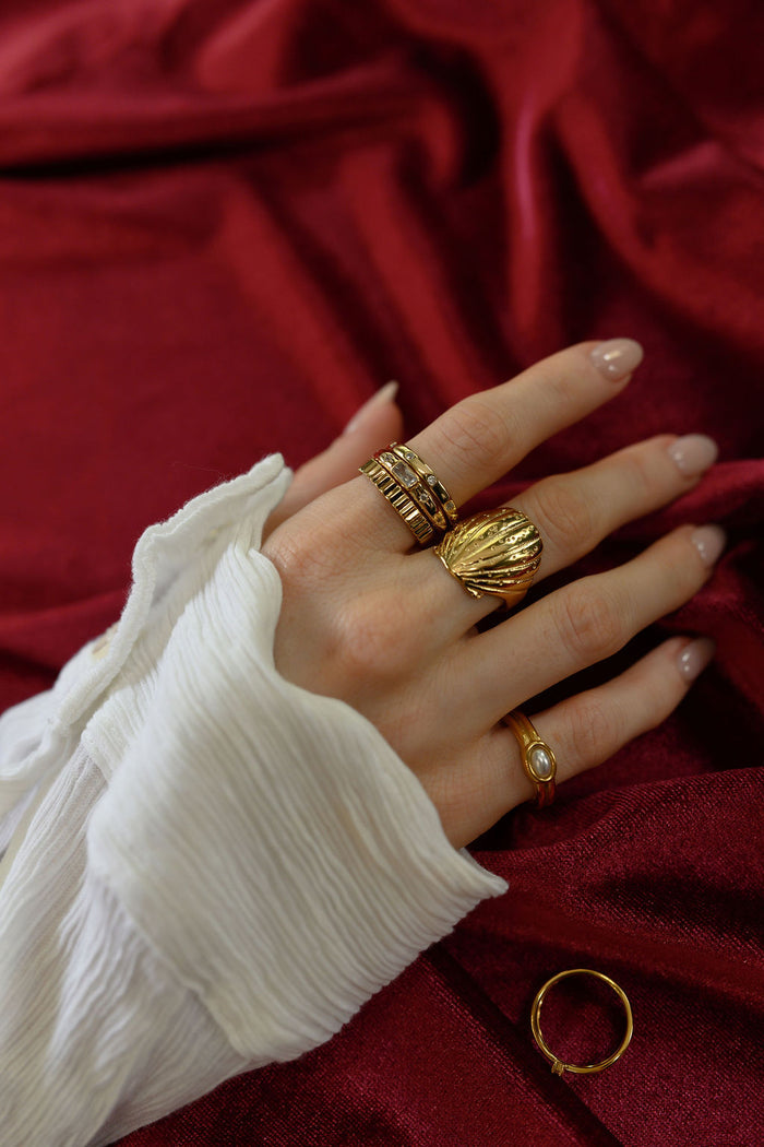 Detail view of the gold Shelly seashell ring on a white background