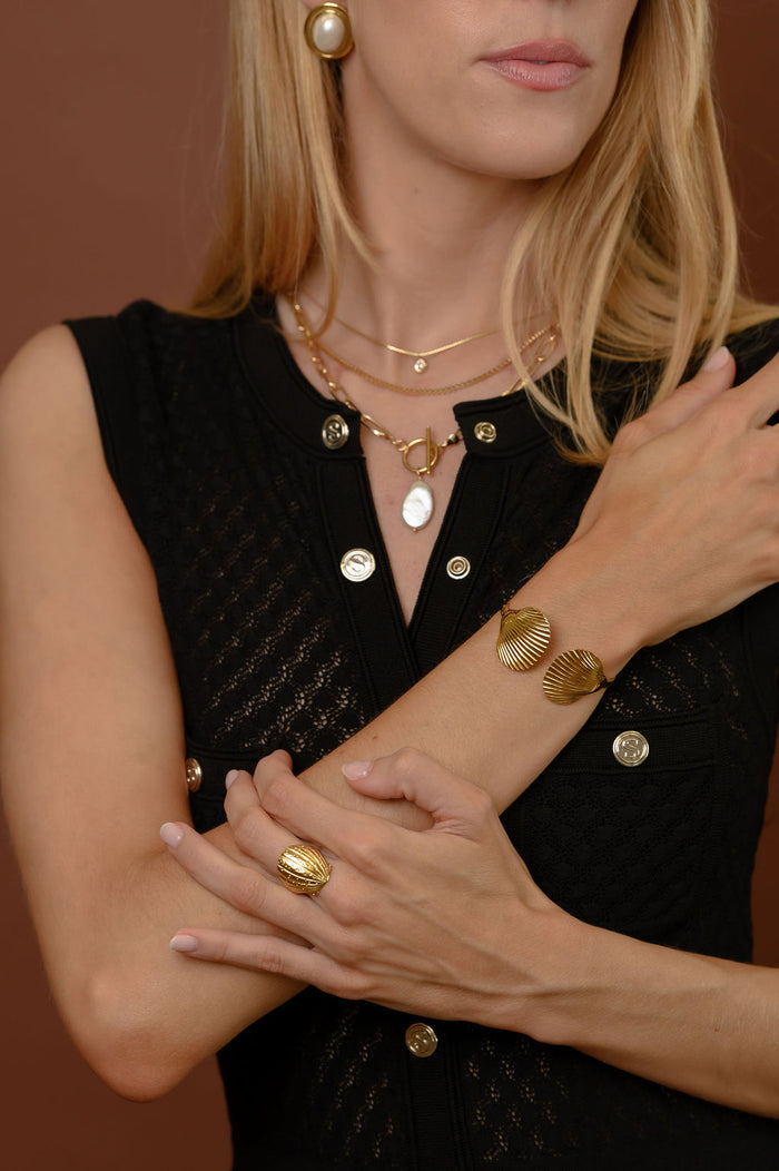 Close view of the gold Shelly seashell ring on a white background
