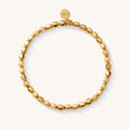 Close up of a gold bead bracelet on a white background