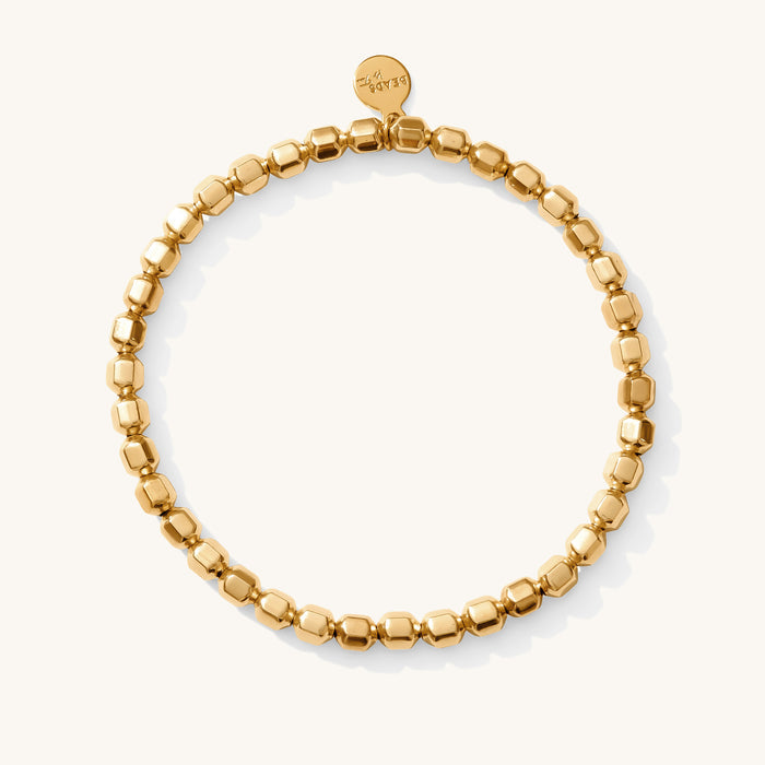 Close up of a gold bead bracelet on a white background