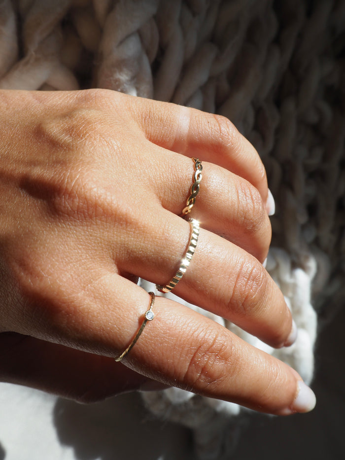 Close up of a hand wearing the gold Sierra twisted band ring