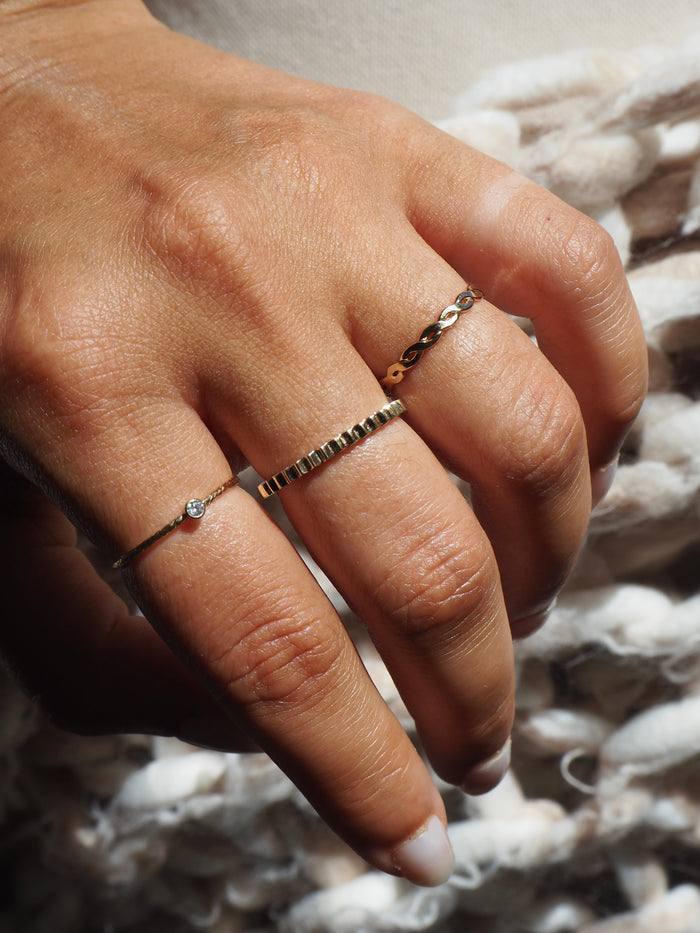 Close up of a hand wearing the Sierra ring stacked with slim gold bands