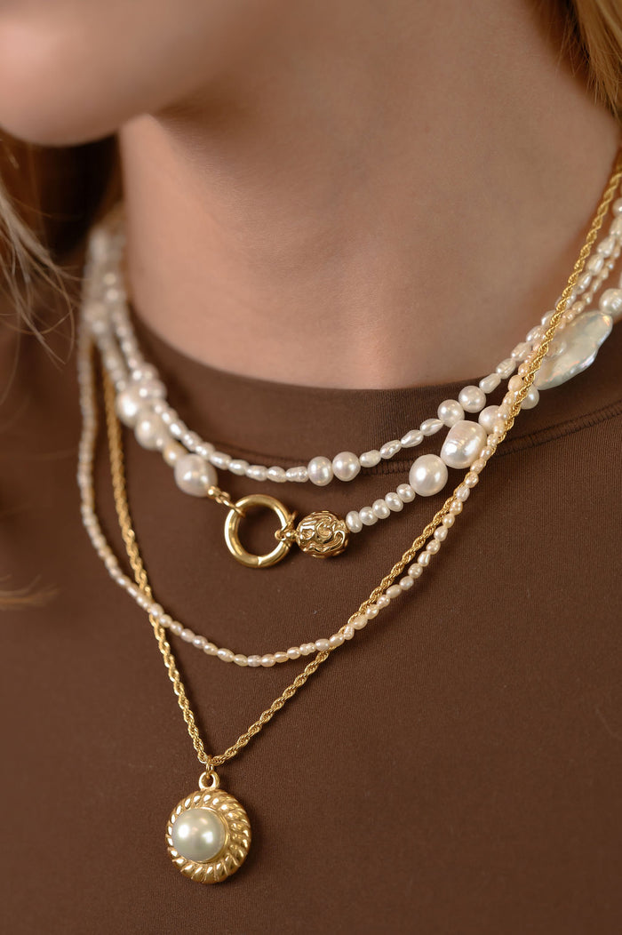 Studio close up of the gold Sirena baroque pearl necklace on a white background