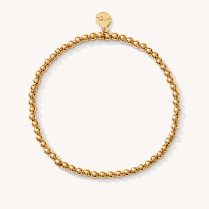 Close up of a gold bead bracelet on a white background