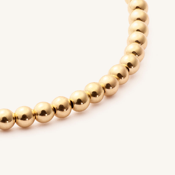 Close up of a gold bead bracelet on a white background