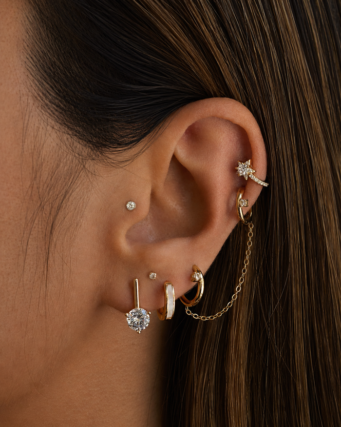 Close-up of an ear with multiple gold and diamond earrings.