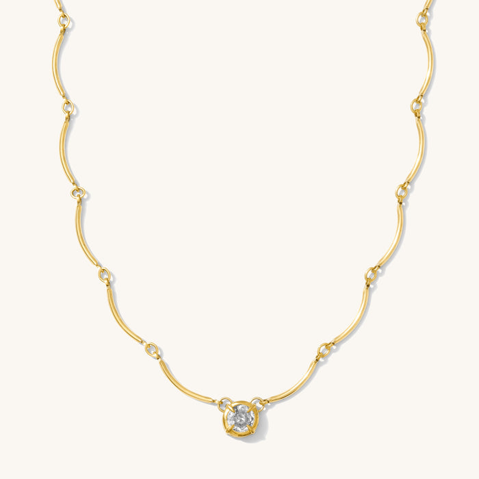 Close up of the gold Solitaire Wave necklace on a white background