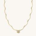 Close up of the gold Solitaire Wave necklace on a white background